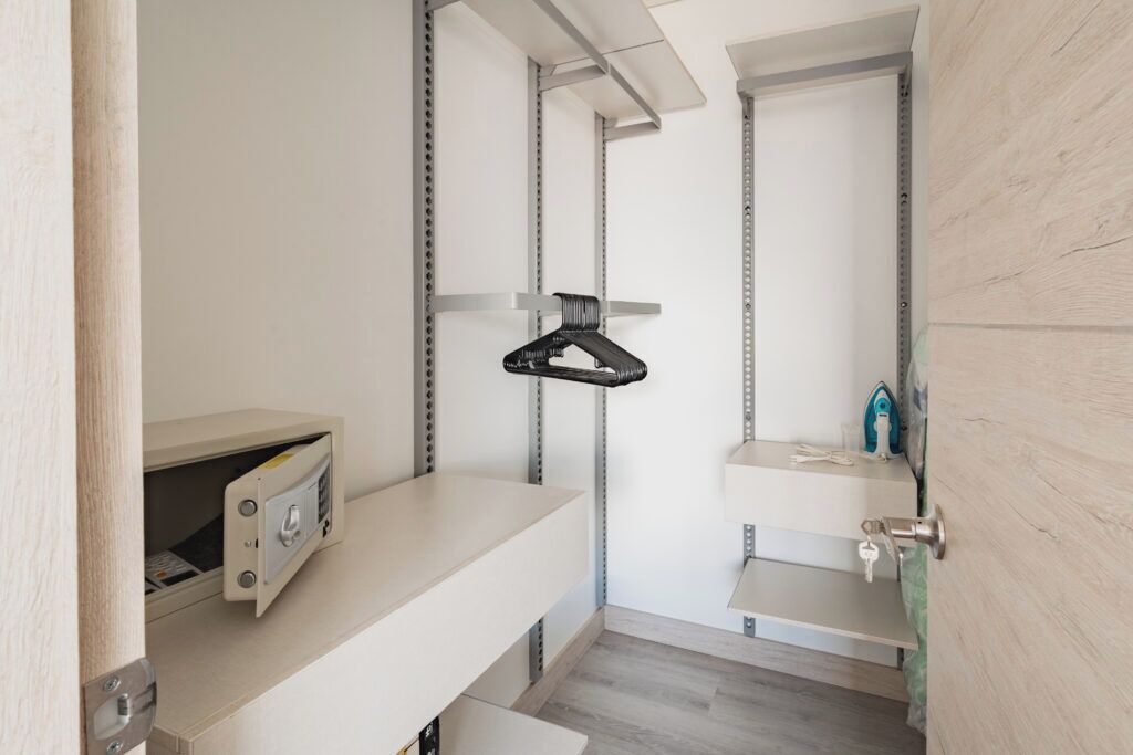 A small, enclosed storage area with metal shelving and a hanging garment rack.