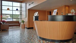 A reception area with a curved wooden desk, a leather sofa, and a tiled floor.