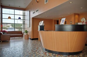 A reception area with a curved wooden desk, a leather sofa, and a tiled floor.