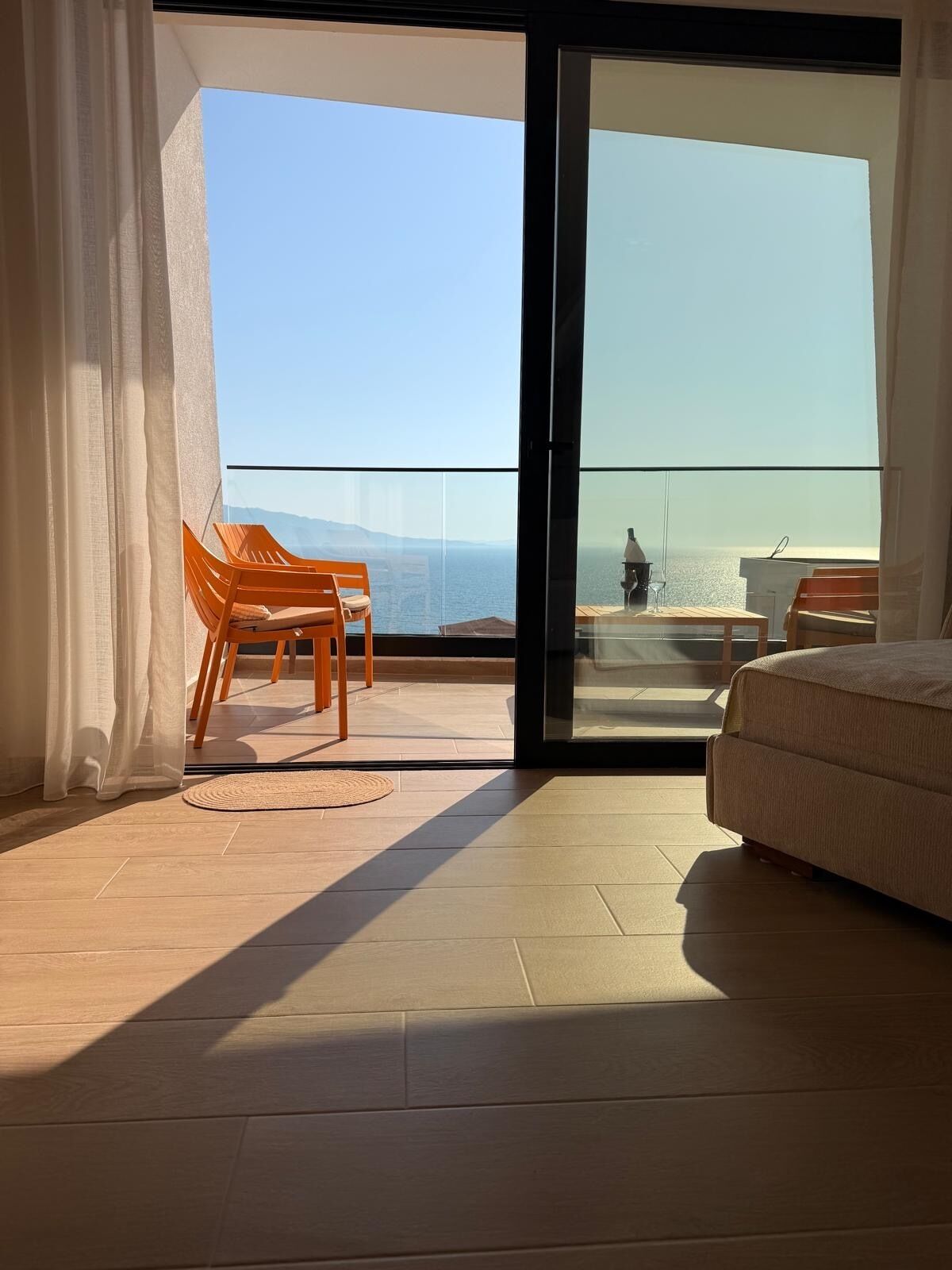 Quarto com uma grande porta de vidro deslizante que dá para uma varanda com vista para o mar.