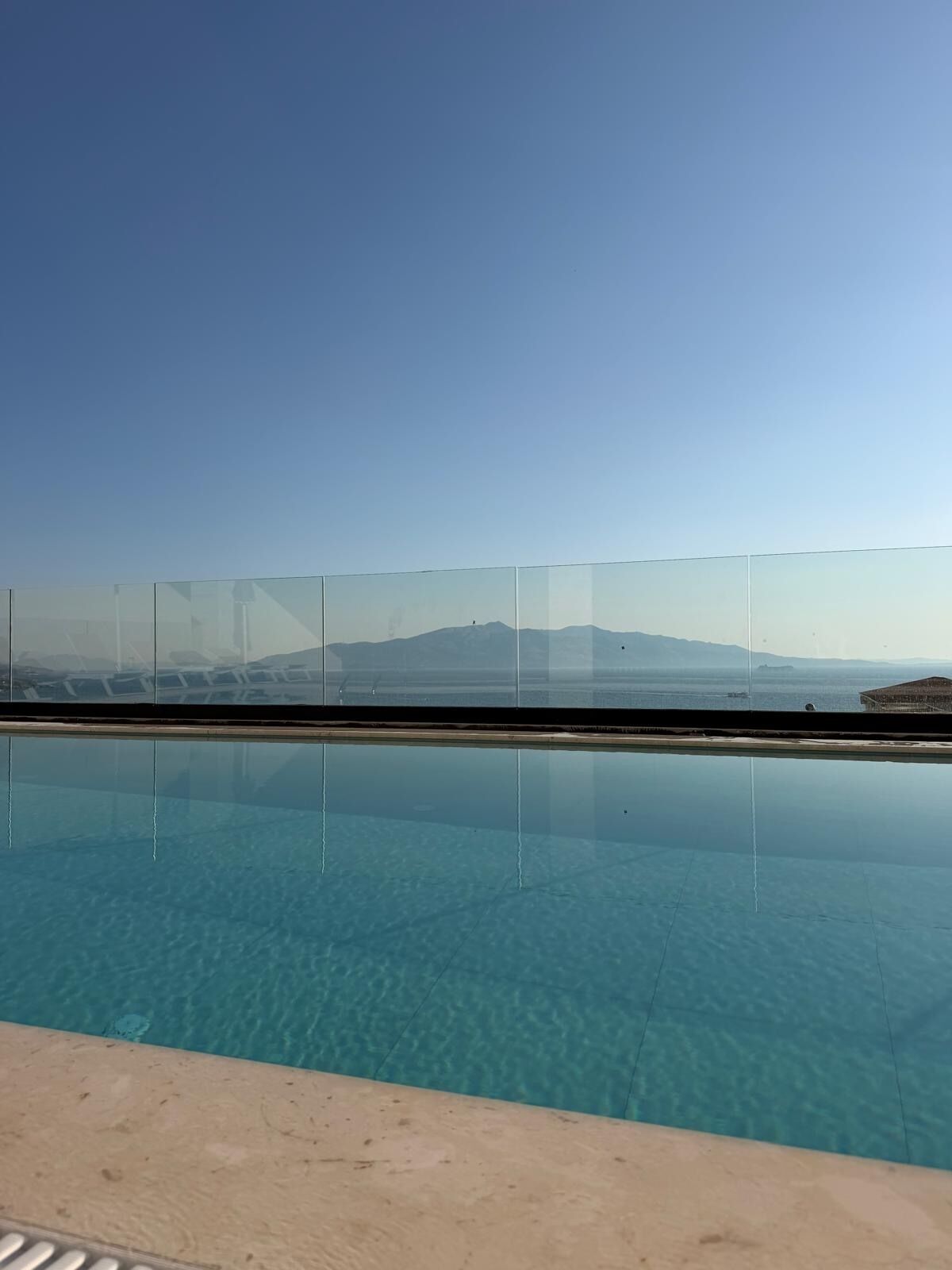 A clear blue pool with a view of distant mountains and a clear sky.