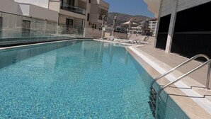 A swimming pool with clear water, surrounded by a poolside area with lounge chairs and umbrellas. - Sea View & Pool, Elite Resort (Saranda)