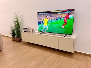 Un televisor sobre un mueble blanco donde se muestra un partido deportivo.