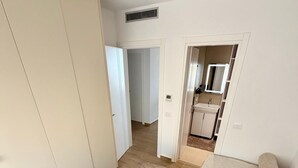A bedroom with a large bed, a wardrobe, and a bathroom visible through an open door. - Sea View & Pool, Elite Resort (Saranda)