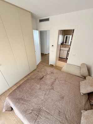 Un dormitorio con una cama grande, un armario y un baño visible a través de una puerta abierta.