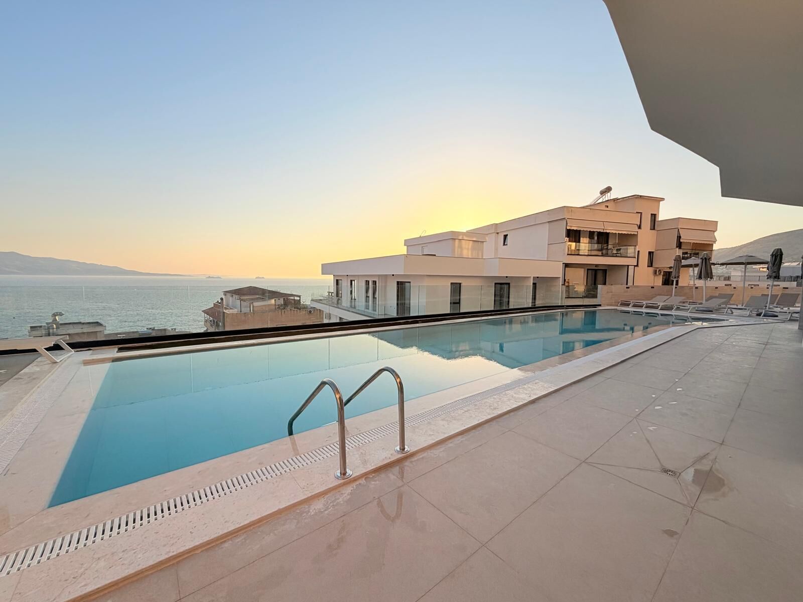 Une piscine avec vue sur la mer et un bâtiment doté de balcons.