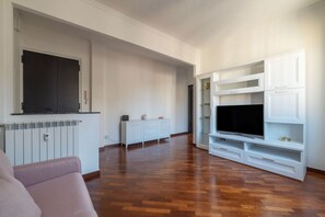 A modern living room with a flat-screen TV, white cabinetry, and a wooden floor. - An elegant 75 sqm apartment, ideal for 4 people, located on the 6th and top floor of a building with an elevator (NOT accessible to people with disabilities).The Lodi metro station is just a 4-minute walk away, making it easy to get around the capital. (Rome)