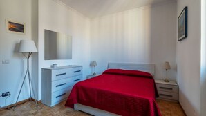 A bedroom with a bed, a dresser, a mirror, and two bedside tables with lamps. - An elegant 75 sqm apartment, ideal for 4 people, located on the 6th and top floor of a building with an elevator (NOT accessible to people with disabilities).The Lodi metro station is just a 4-minute walk away, making it easy to get around the capital. (Rome)