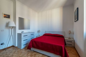 A bedroom with a bed, a dresser, a mirror, and two bedside tables with lamps. - An elegant 75 sqm apartment, ideal for 4 people, located on the 6th and top floor of a building with an elevator (NOT accessible to people with disabilities).The Lodi metro station is just a 4-minute walk away, making it easy to get around the capital. (Rome)