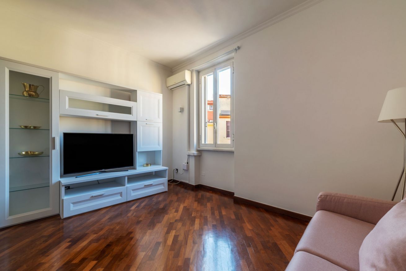 A living room with a flat-screen TV, built-in shelving, and a window with a view.