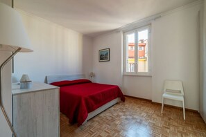 A bedroom with a bed, a chair, a desk, a window, and a painting on the wall. - An elegant 75 sqm apartment, ideal for 4 people, located on the 6th and top floor of a building with an elevator (NOT accessible to people with disabilities).The Lodi metro station is just a 4-minute walk away, making it easy to get around the capital. (Rome)