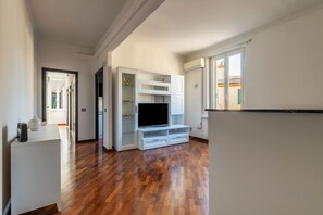 A spacious living area with a wooden floor, built-in entertainment unit, and a large window. - An elegant 75 sqm apartment, ideal for 4 people, located on the 6th and top floor of a building with an elevator (NOT accessible to people with disabilities).The Lodi metro station is just a 4-minute walk away, making it easy to get around the capital. (Rome)