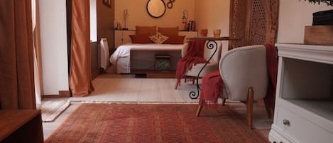 A bedroom with a bed, a chair, a nightstand, a dresser, and a patterned rug.