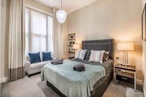 Una habitación de hotel con cama, sofá, escritorio y lámpara.