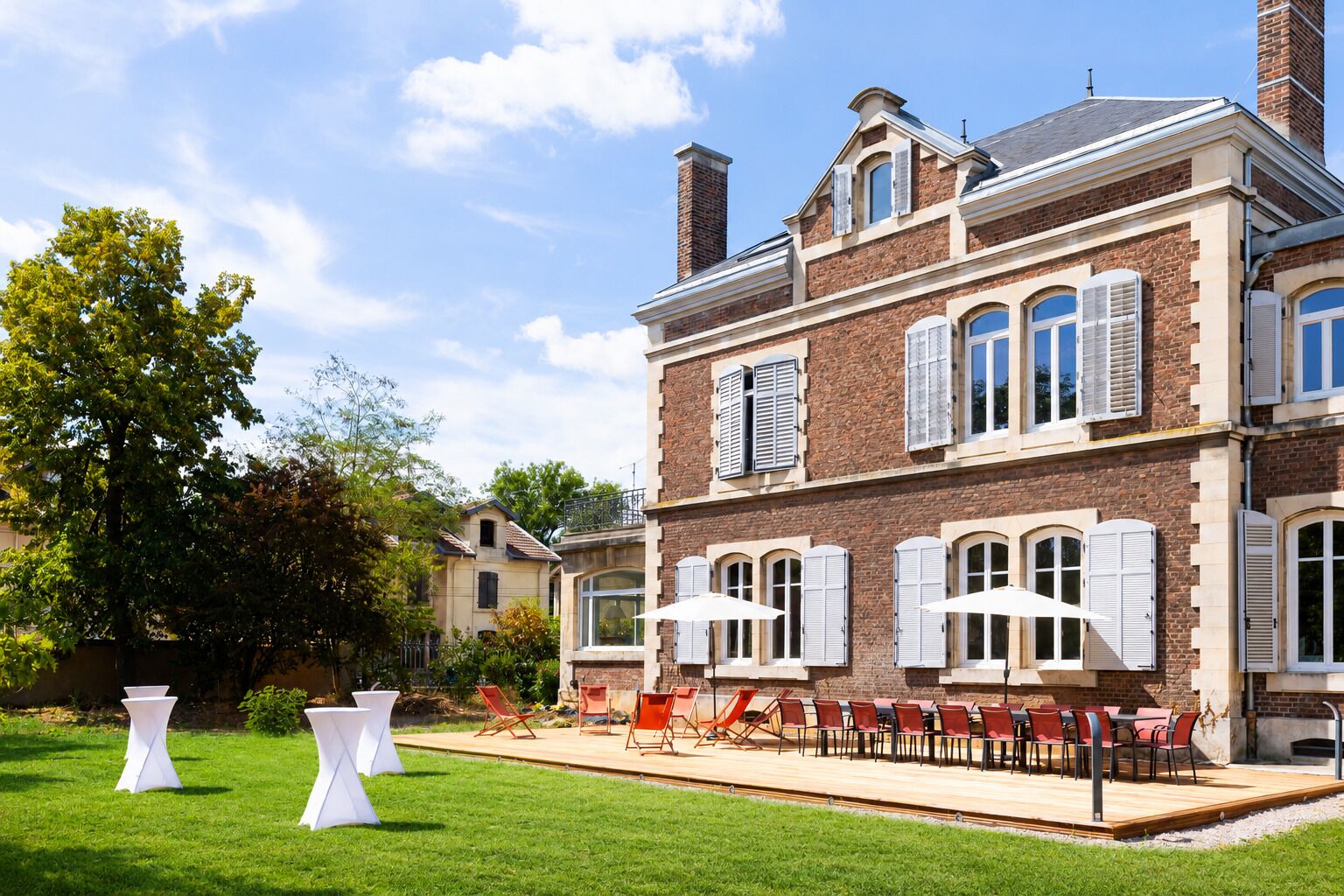A two-story brick building with a patio area featuring outdoor seating and tables.