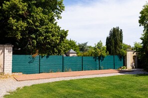 A fenced backyard with a grassy lawn, a brick pathway, and a stone wall. - Le Domaine d'Amélie: An Elegant Vacation Rental on the Outskirts of Nancy (Dombasle-sur-Meurthe)