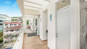 Ein Hotelgang mit Blick auf die Stadt, einer Hängematte und einer Tür mit Symbolen für WC für Damen und Herren.