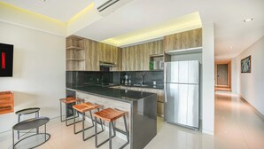 Eine moderne Küche mit einer zentralen Kochinsel, Barhocker und einem Edelstahl-Kühlschrank.