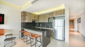 A modern kitchen with a central island, bar stools, and a stainless steel refrigerator. - Torre Ku, Near the Beach & Rooftop Pool (Puerto Vallarta)