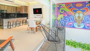 Una cucina moderna con TV a schermo piatto, mobili in legno e zona pranzo con sedie e tavolo.