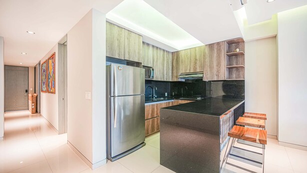 Una cucina moderna con frigorifero in acciaio inossidabile, mobili in legno e piano di lavoro nero.