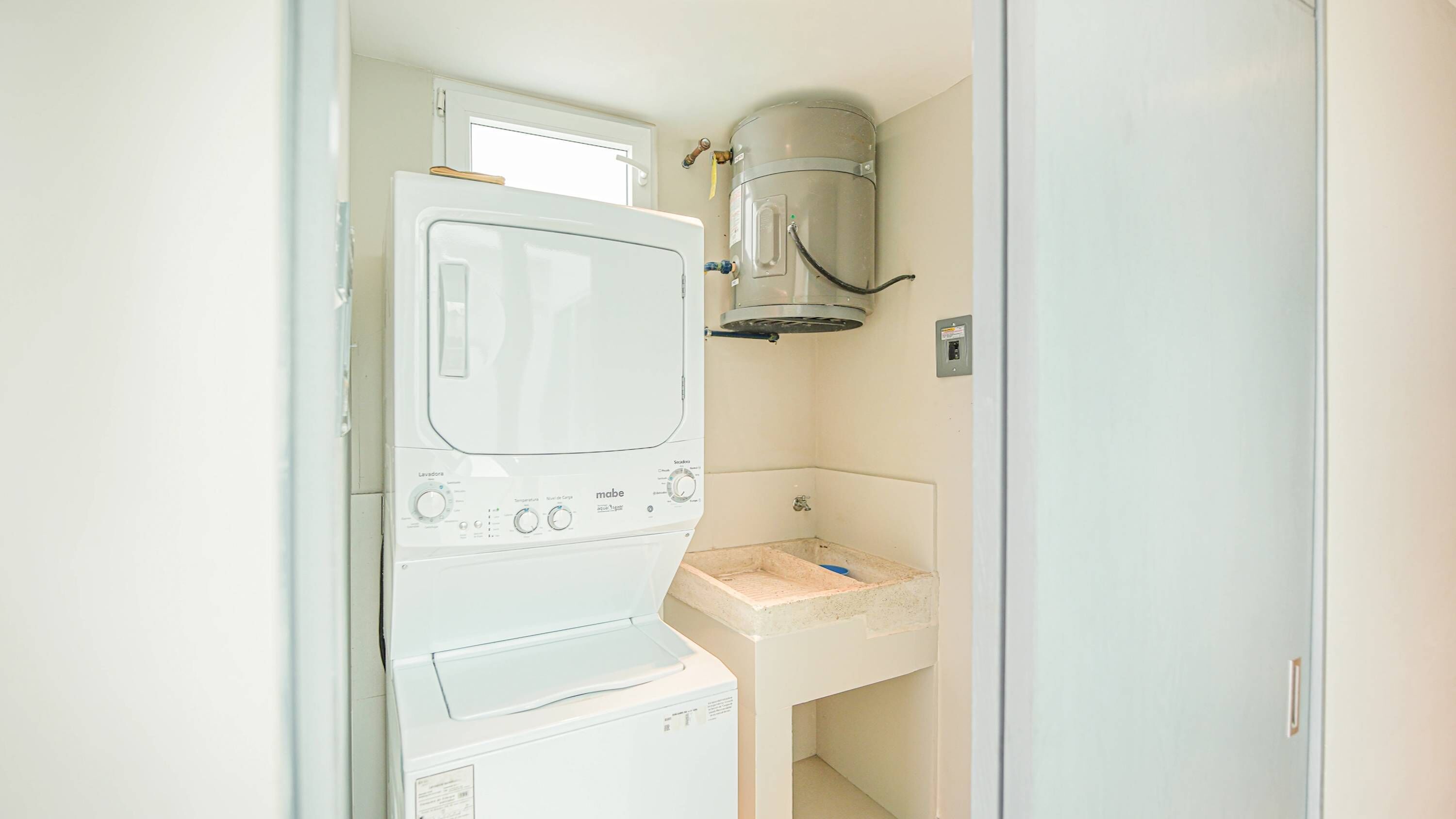 A compact laundry room with a washing machine, a dryer, and a sink.