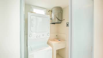 A compact laundry room with a washing machine, a dryer, and a sink.
