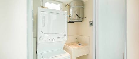 A compact laundry room with a washing machine, a dryer, and a sink.