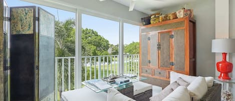 Ein Balkon mit Korbmöbeln, einem Glastisch und Blick ins Grüne.