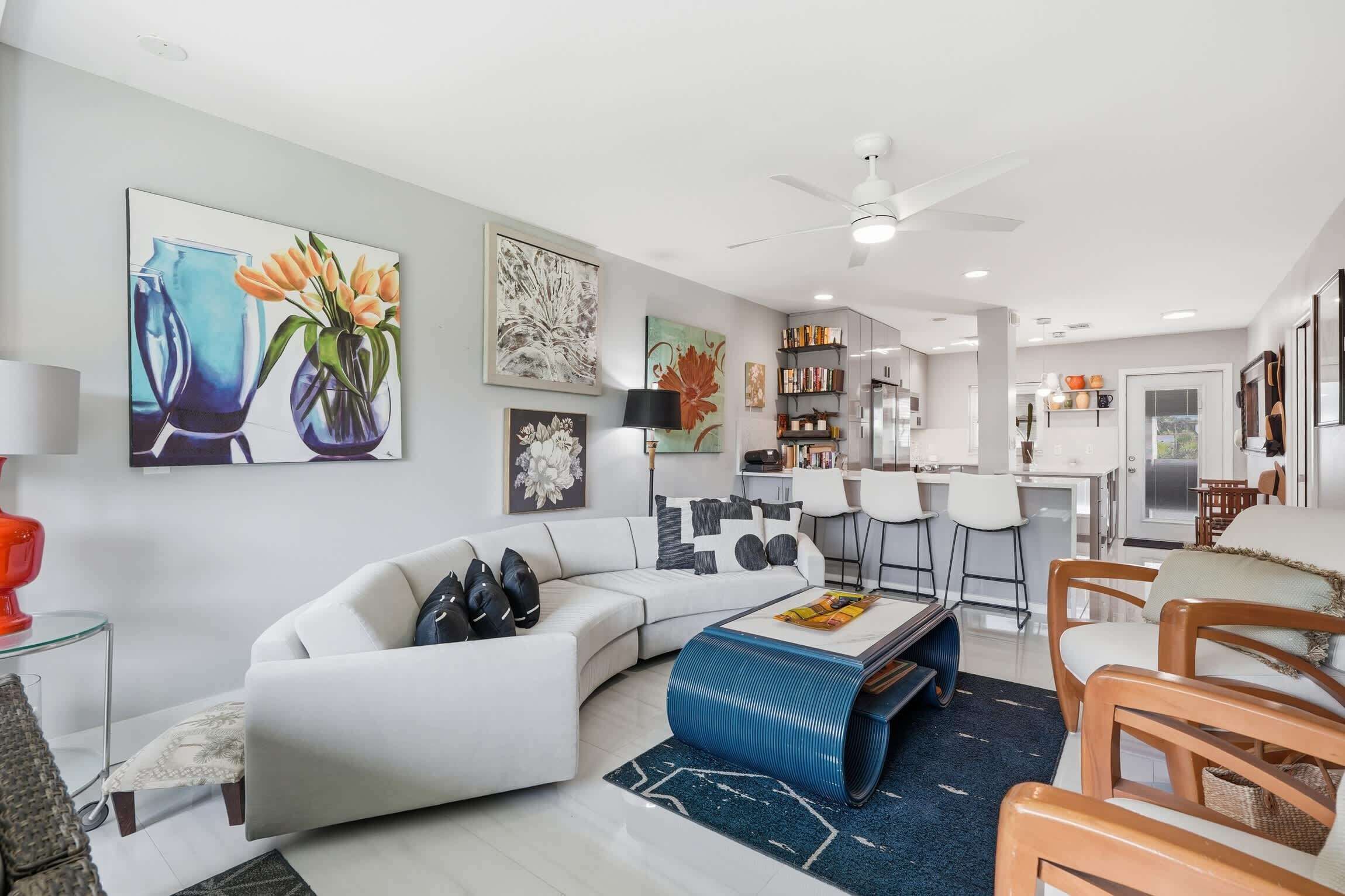 A modern living room with a white sofa, a coffee table, and a dining area with wooden chairs.