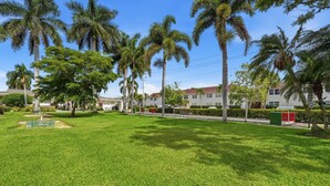 A well-maintained grassy area with palm trees and a clear sky. - Close to Beach, Shops, Downtown - Great for Snowbirds (Naples)