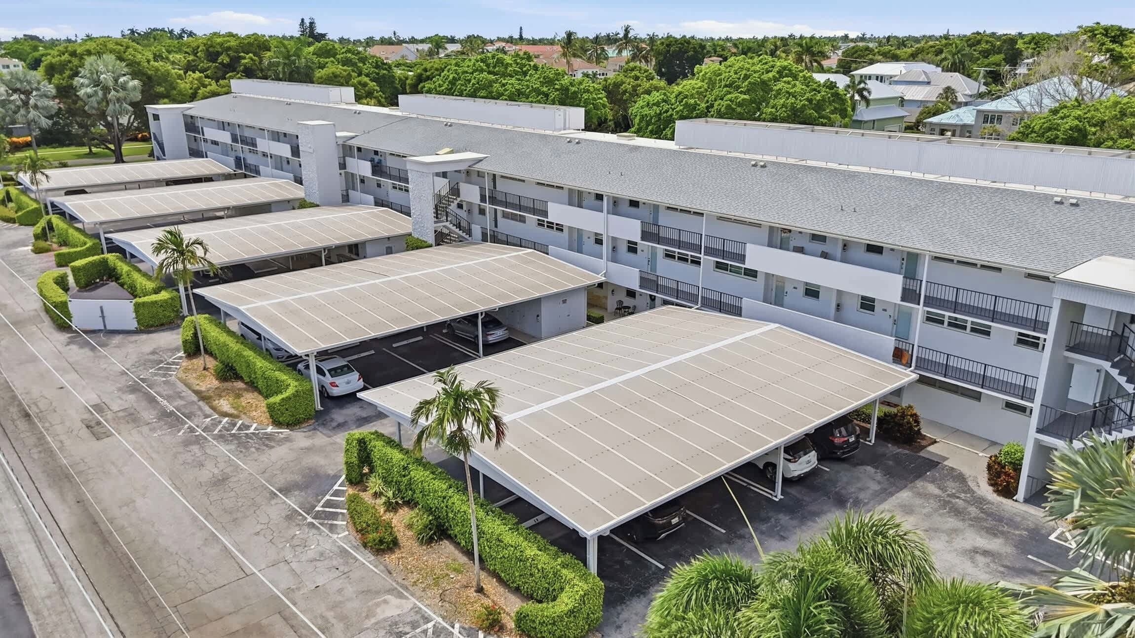 A multi-story building with a parking area and solar panels.