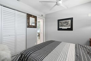 A bedroom with a bed, a ceiling fan, a framed picture on the wall, and a closet with sliding doors. - Close to Beach, Shops, Downtown - Great for Snowbirds (Naples)