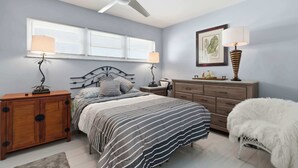 A bedroom with a bed, bedside tables, a dresser, a ceiling fan, and a window with blinds. - Close to Beach, Shops, Downtown - Great for Snowbirds (Naples)