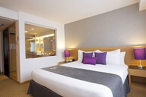 A hotel room with a large bed, a mirror, a nightstand, and a lamp. - Eurobuilding Hotel and Suites Caracas (Caracas)