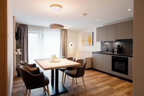 A modern kitchen with a dining area, wooden flooring, and contemporary furniture. - Apartment Garnera 24 (Gaschurn)