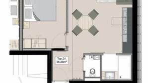Hotellihuoneen pohjapiirros, jossa on sänky, pieni kylpyhuone, oleskelualue pöydällä sekä pieni keittiönurkkaus.