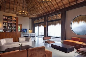 A spacious lounge area with a high ceiling, a bar with a wooden cabinet, and a large round mirror. - 98 Acres Resort and Spa (Ella)