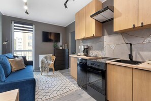 A modern kitchen with wooden cabinets, a built-in oven, and a countertop. - Cosy Apartment for 4 People | Workspace (Gdynia)