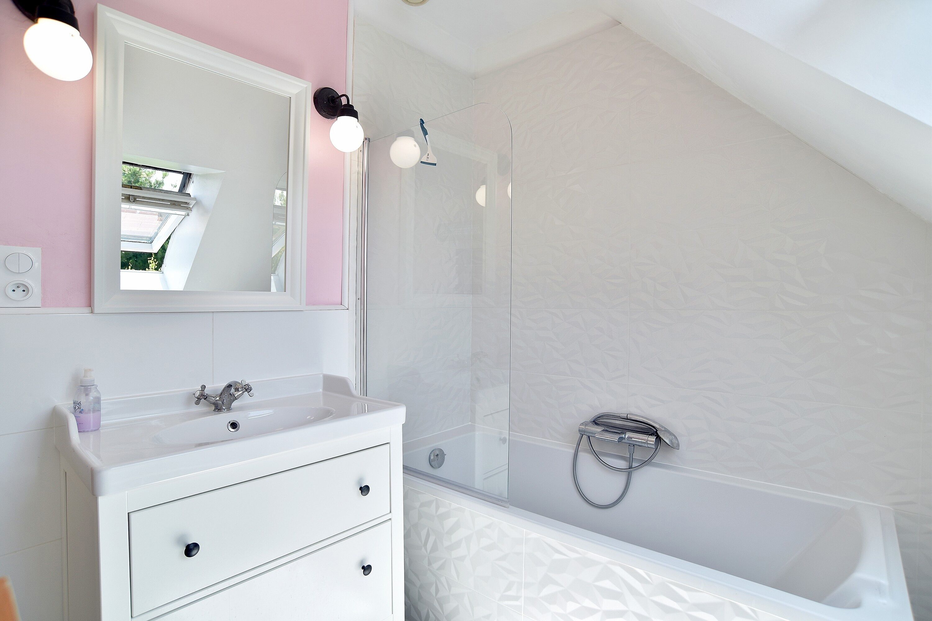 Une salle de bain avec un meuble-lavabo blanc, un miroir, une douche avec une porte en verre et une baignoire.