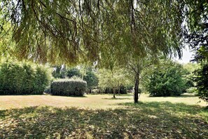 Un parc avec une pelouse, une balançoire en bois et divers arbres.