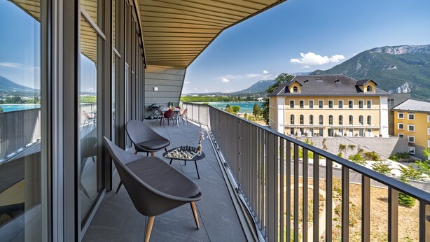 A balcony with two chairs and a chessboard, overlooking a mountainous landscape and a body of water. - Penthouse Annecy74 - Vue panoramique sur le lac (Annecy)