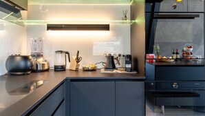 A modern kitchen with a built-in coffee machine, a kettle, and a blender on the counter. - Penthouse Annecy74 - Vue panoramique sur le lac (Annecy)