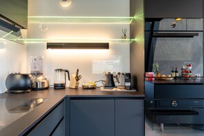 A modern kitchen with a built-in coffee machine, a kettle, and a blender on the counter. - Penthouse Annecy74 - Vue panoramique sur le lac (Annecy)