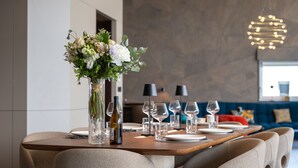 A dining table set with plates, glasses, and a bottle, surrounded by upholstered chairs. - Penthouse Annecy74 - Vue panoramique sur le lac (Annecy)