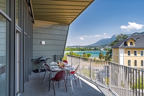 A balcony with a table set for dining, overlooking a scenic view of a lake and mountains. - Penthouse Annecy74 - Vue panoramique sur le lac (Annecy)