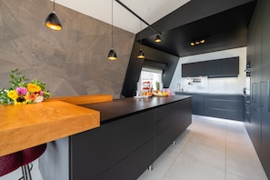 A modern kitchen with a wooden island, black cabinets, and pendant lighting. - Penthouse Annecy74 - Vue panoramique sur le lac (Annecy)