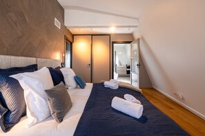 A modern hotel room with a large bed, a wardrobe, and a bathroom visible through an open door. - Penthouse Annecy74 - Vue panoramique sur le lac (Annecy)