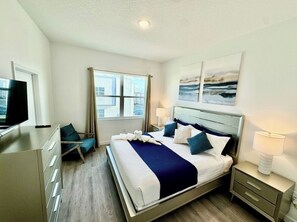 Ein Hotelzimmer mit Bett, Schreibtisch, Stuhl, Fernseher und Bildern an der Wand.