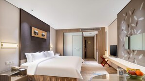 Ein modernes Hotelzimmer mit einem großen Bett, einem Nachttisch und einem Fernseher auf einem Schrank.